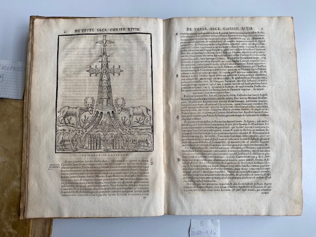 libro aperto con illustrazione di una croce al centro e due cervi accanto